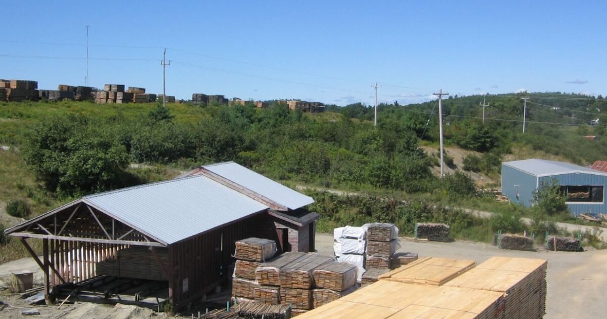 Exterior view of a lumber sawmill site with stacked timber