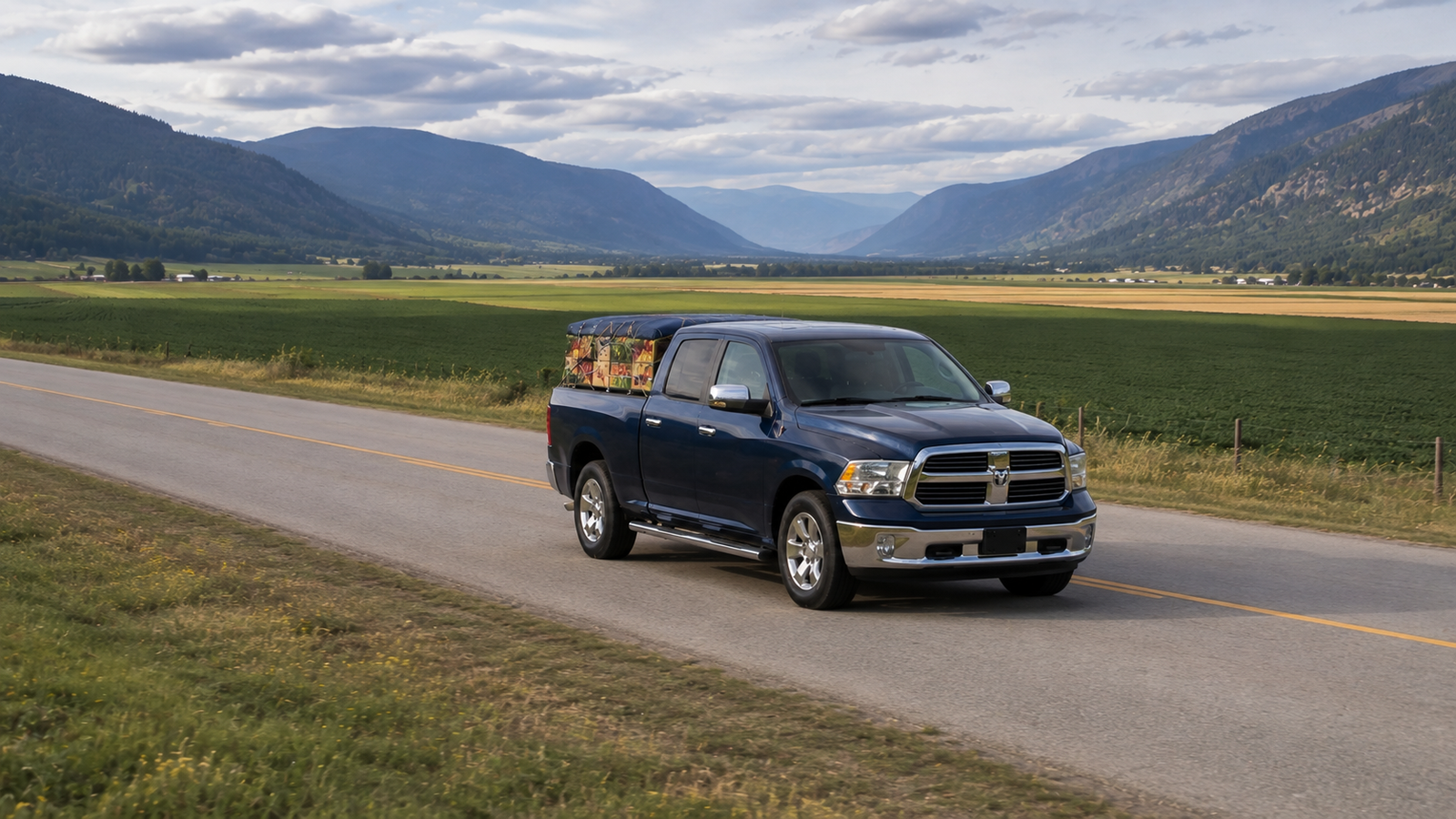 Canyon Runner Hotshot truck driving through the Creston Valley with mountains and farmland behind, front three-quarter angle