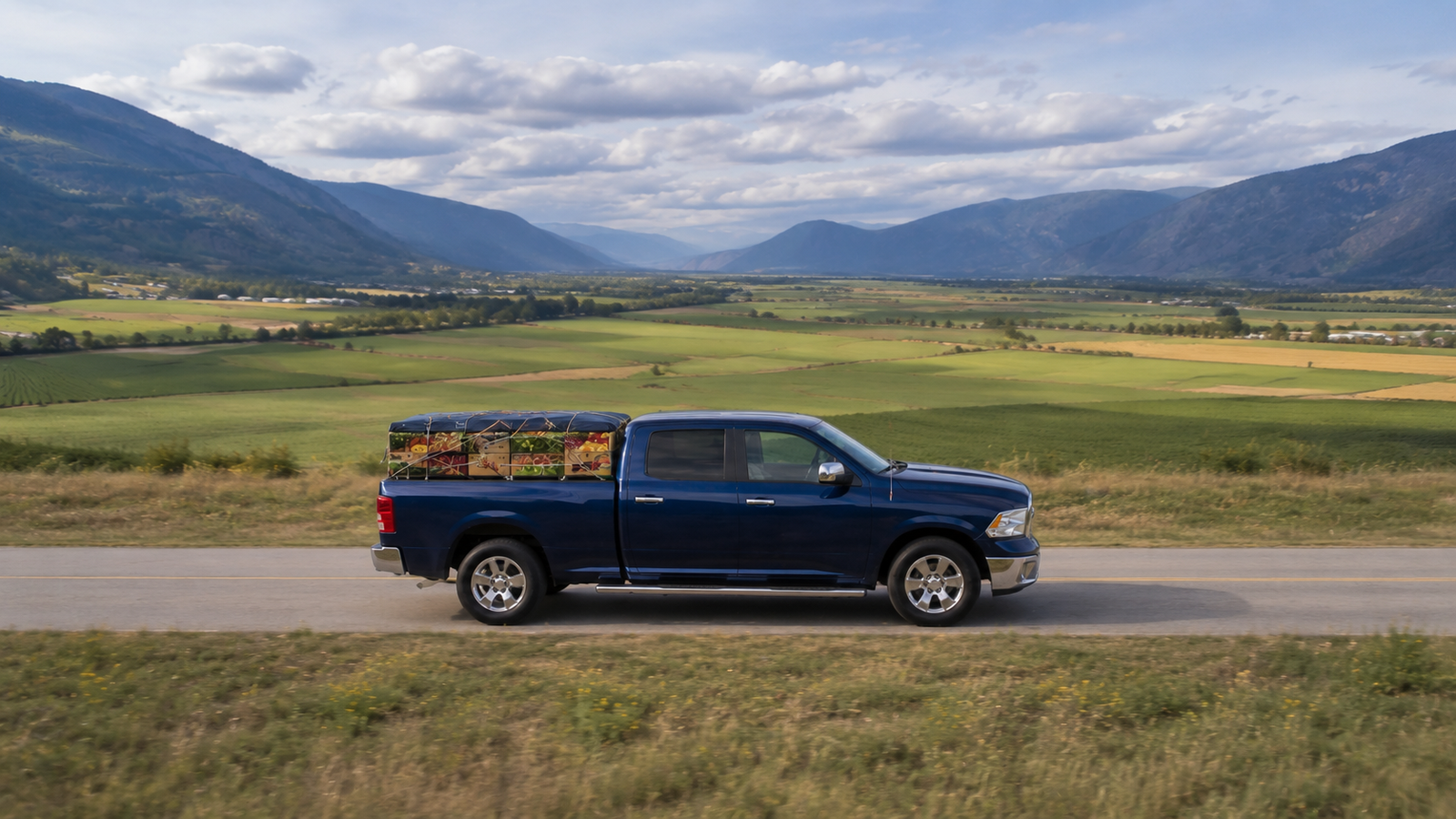 Canyon Runner Hotshot truck side profile with produce crates, Creston Valley farmland and mountains in the background