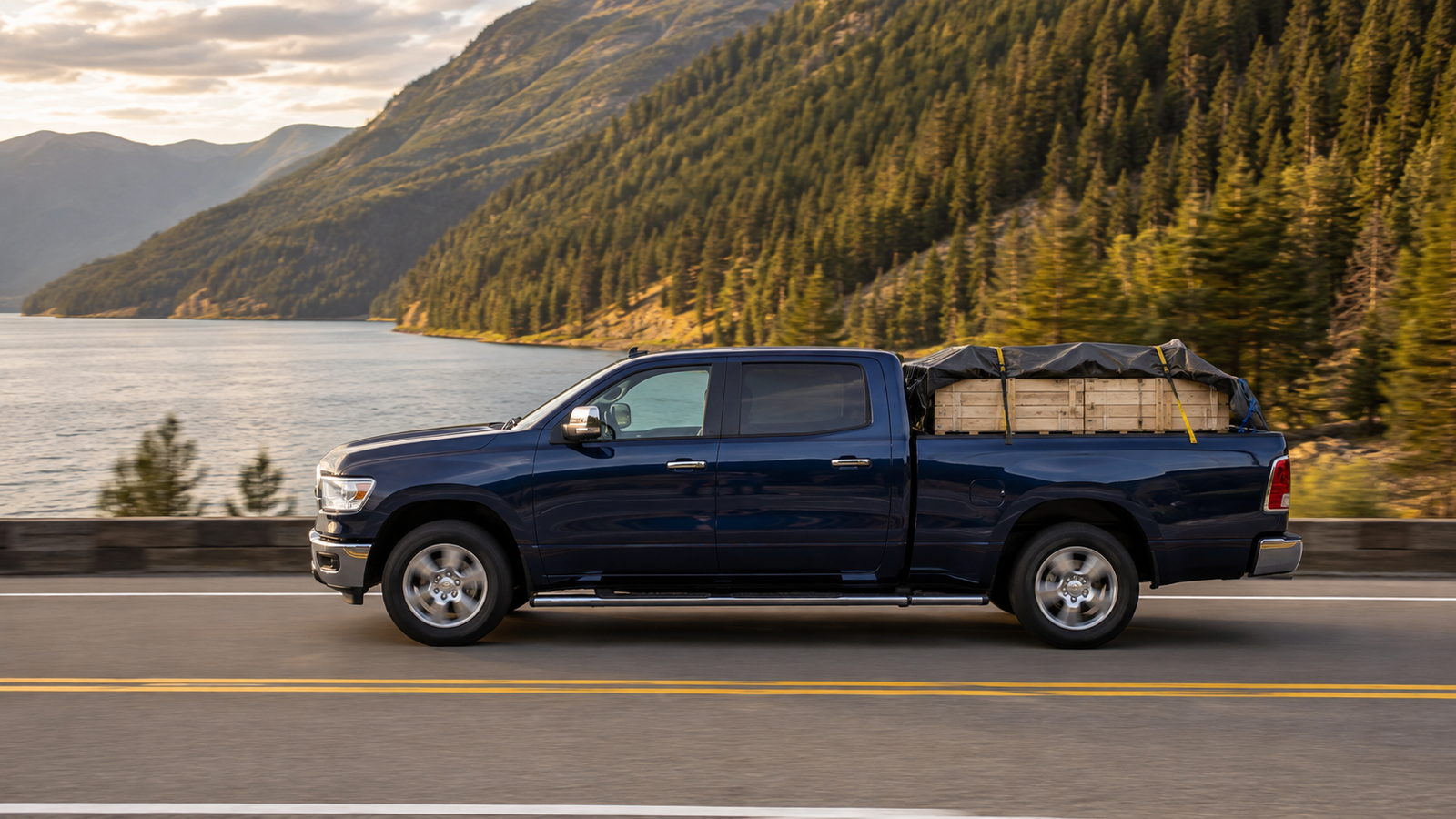 Canyon Runner Hotshot navy blue pickup truck side profile with strapped crates in the bed, driving along the shore of Kootenay Lake near Nelson, BC