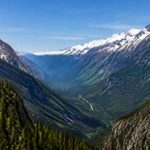 Mountain pass valley view near Revelstoke, BC, with snow-capped peaks and forested slopes